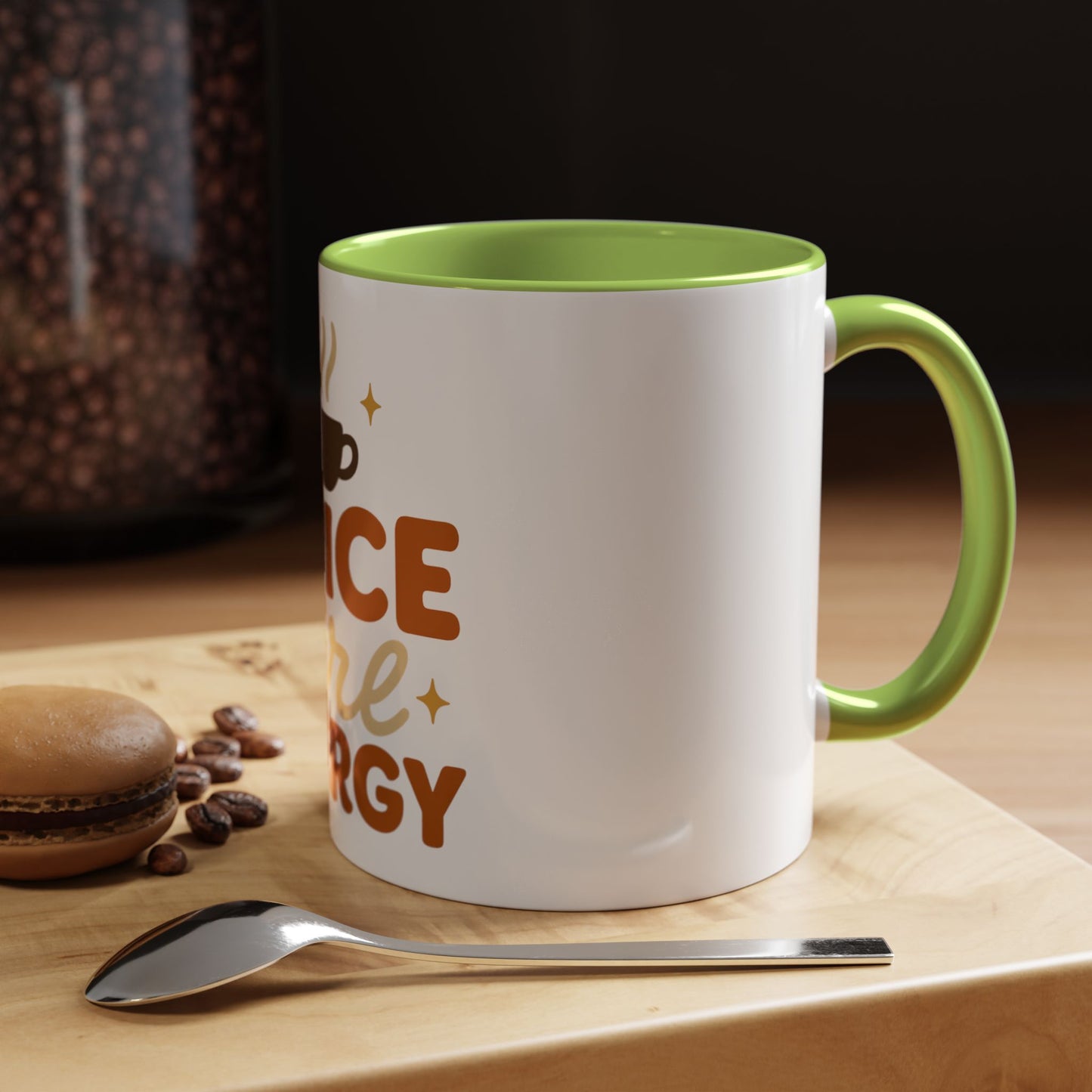 Green “Spice Girl Energy” accent mug on cozy coffee table — white ceramic mug with green handle surrounded by coffee beans and macaron.