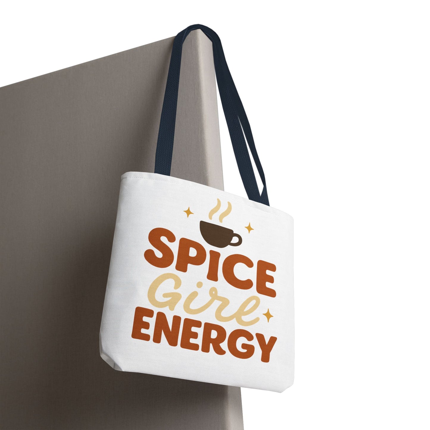 White “Spice Girl Energy” tote bag with navy handles hanging on wall — trendy coffee aesthetic tote for pumpkin spice lovers.