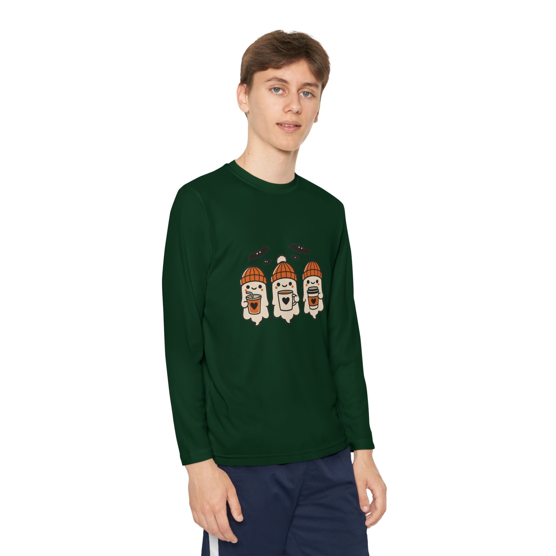 Young male wearing dark green long sleeve Halloween shirt with three cute ghosts in orange beanies holding coffee mugs, surrounded by bats.
