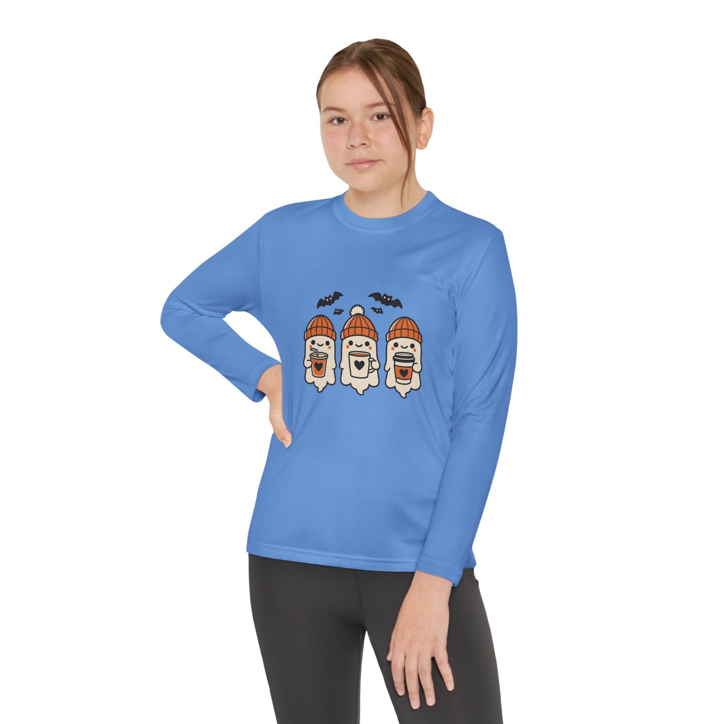 Young Woman wearing light blue long sleeve Halloween shirt featuring three cute ghosts in orange beanies holding coffee mugs with bats overhead.
