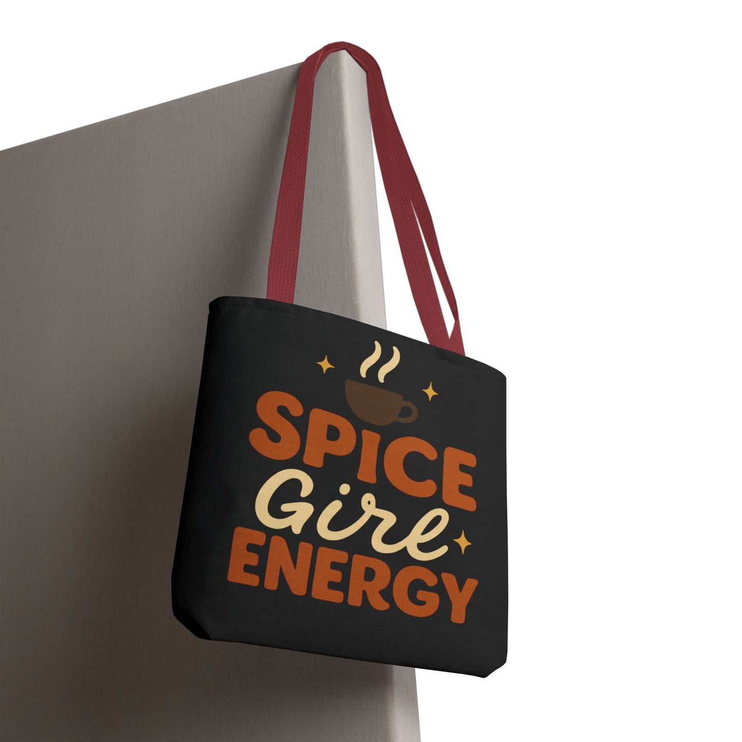 Black “Spice Girl Energy” tote bag with red straps hanging on wall — trendy fall accessory for pumpkin spice and coffee fans.