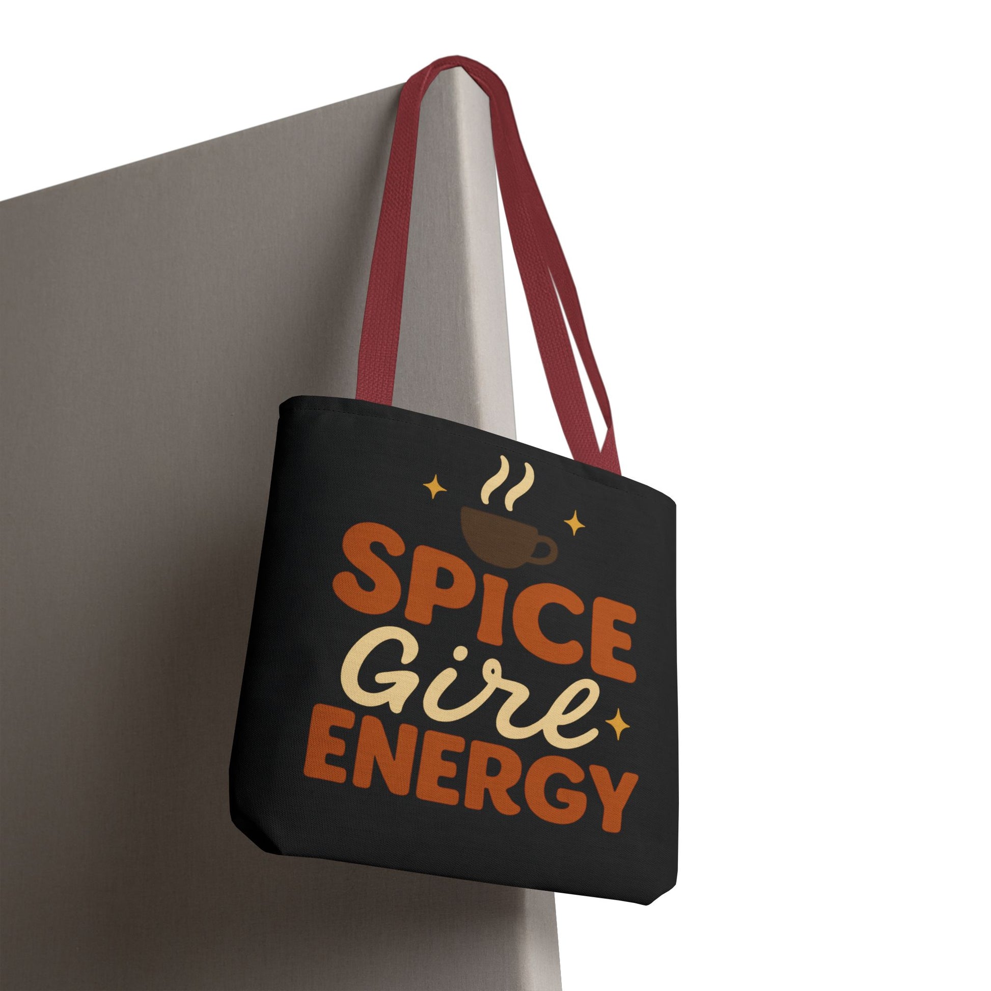 Black “Spice Girl Energy” tote bag with red straps hanging on wall — trendy fall accessory for pumpkin spice and coffee fans.