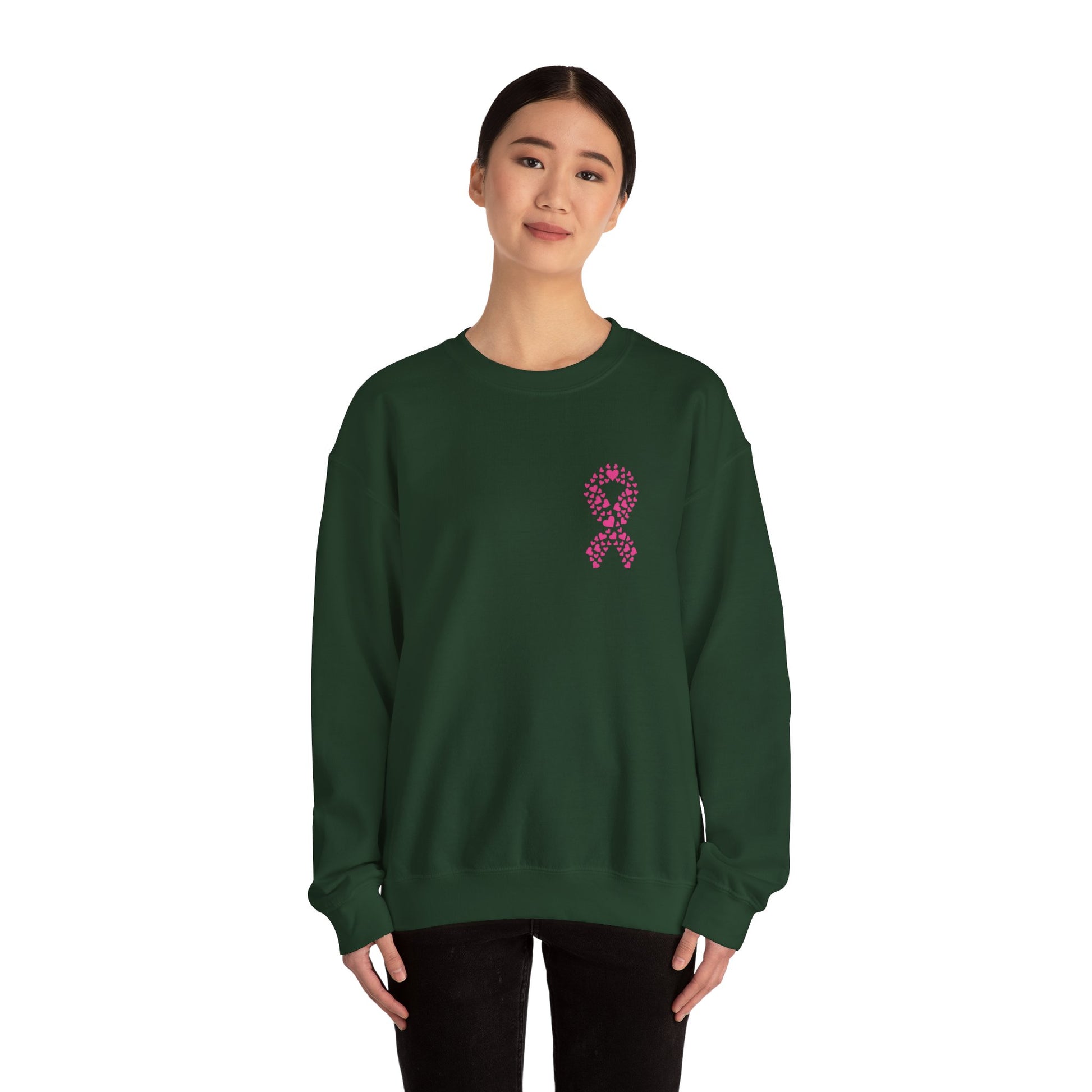 Woman wearing forest-green breast cancer awareness crewneck sweatshirt featuring pink ribbon of hearts graphic, Makin’ It by Lady Ev.