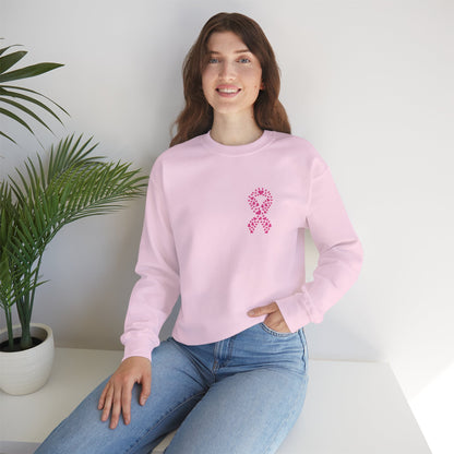 Woman seated wearing light pink breast cancer awareness crewneck sweatshirt with pink ribbon of hearts design, Makin’ It by Lady Ev