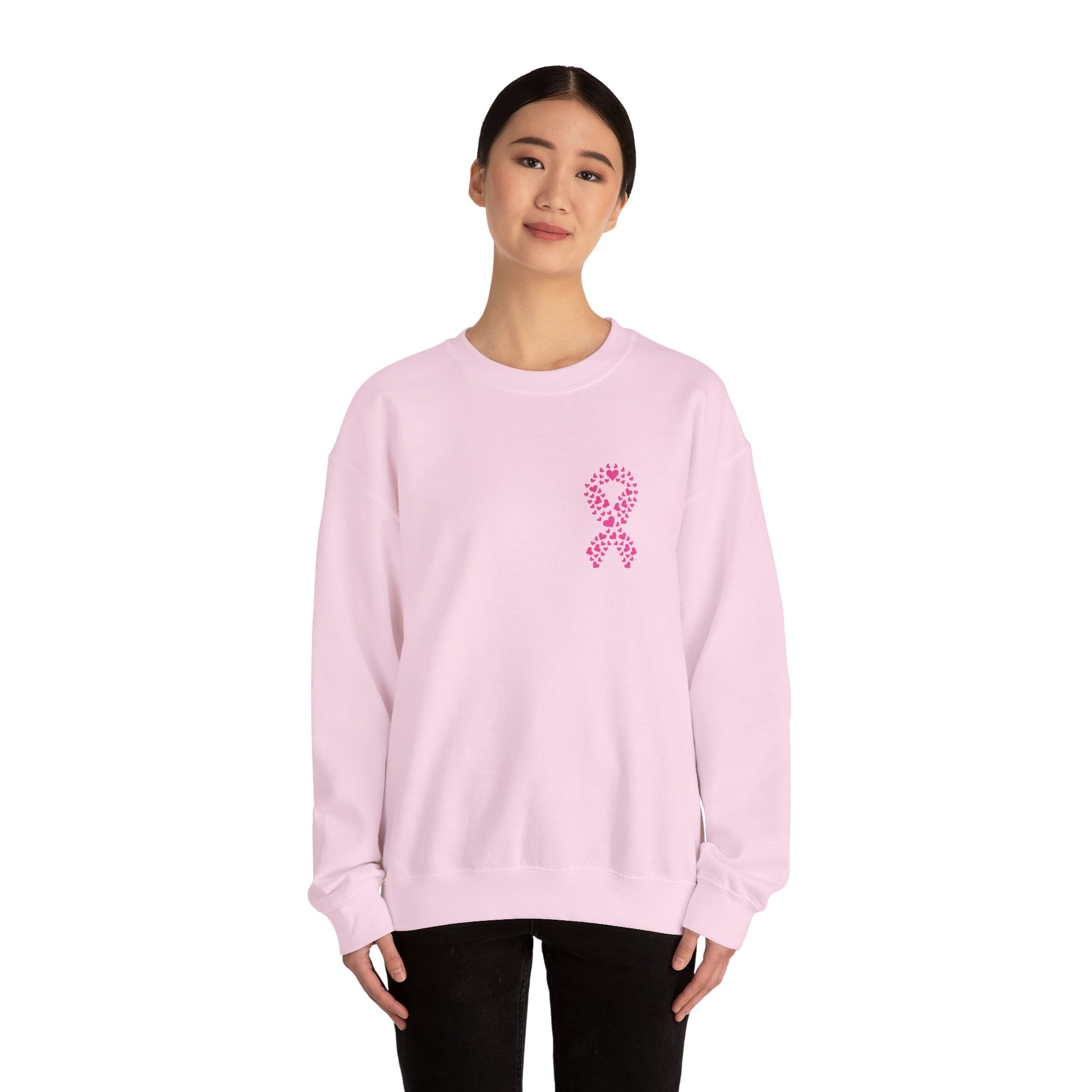 Woman wearing light pink breast cancer awareness crewneck sweatshirt featuring heart-shaped pink ribbon, Makin’ It by Lady Ev
