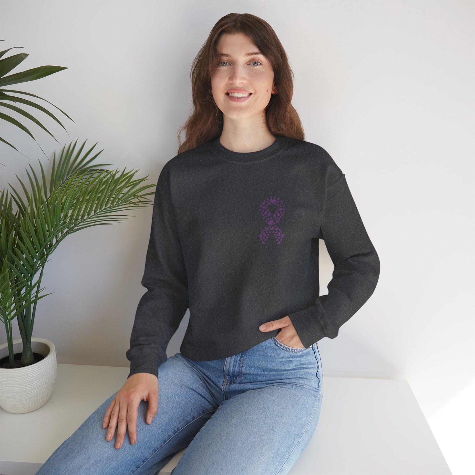Woman seated in charcoal gray domestic violence awareness crewneck sweatshirt with purple heart ribbon design, Makin’ It by Lady Ev.