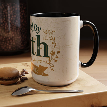 Lifestyle image of black “Fueled by Faith & Pumpkin Spice” 15oz accent mug — Christian fall mug on wooden table beside macaron and coffee spoon.
