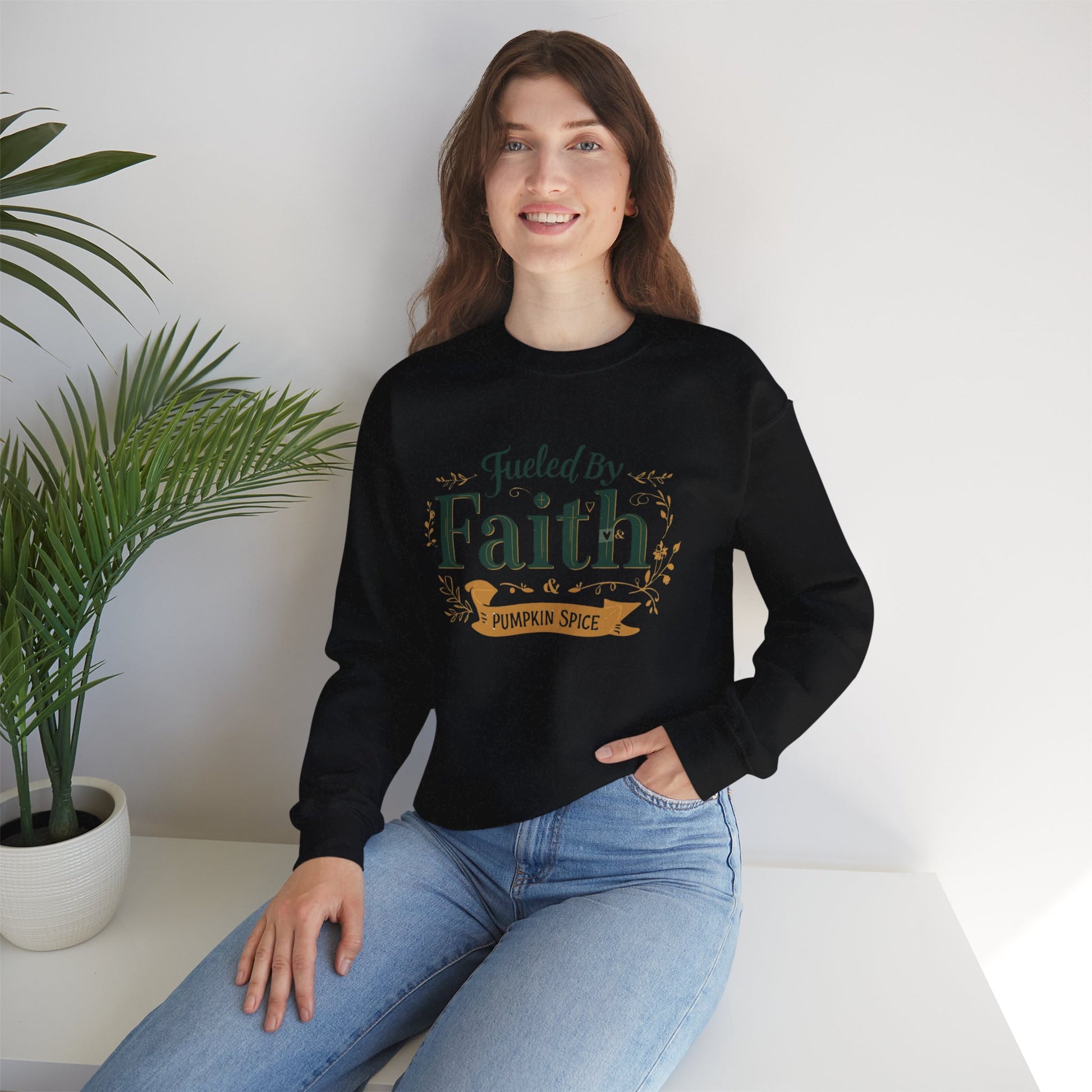 Woman sitting indoors wearing black “Fueled by Faith & Pumpkin Spice” crewneck sweatshirt — cozy Christian lifestyle apparel for fall.