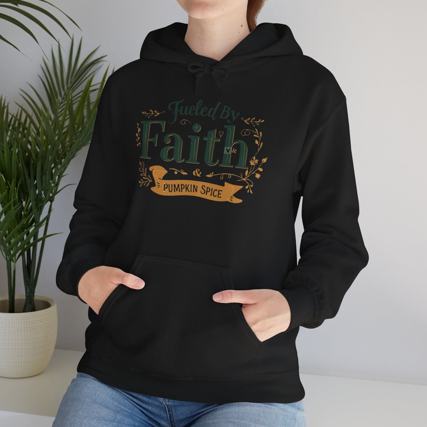 Lifestyle image of woman wearing black “Fueled by Faith & Pumpkin Spice” hoodie — cozy Christian fall fashion look.