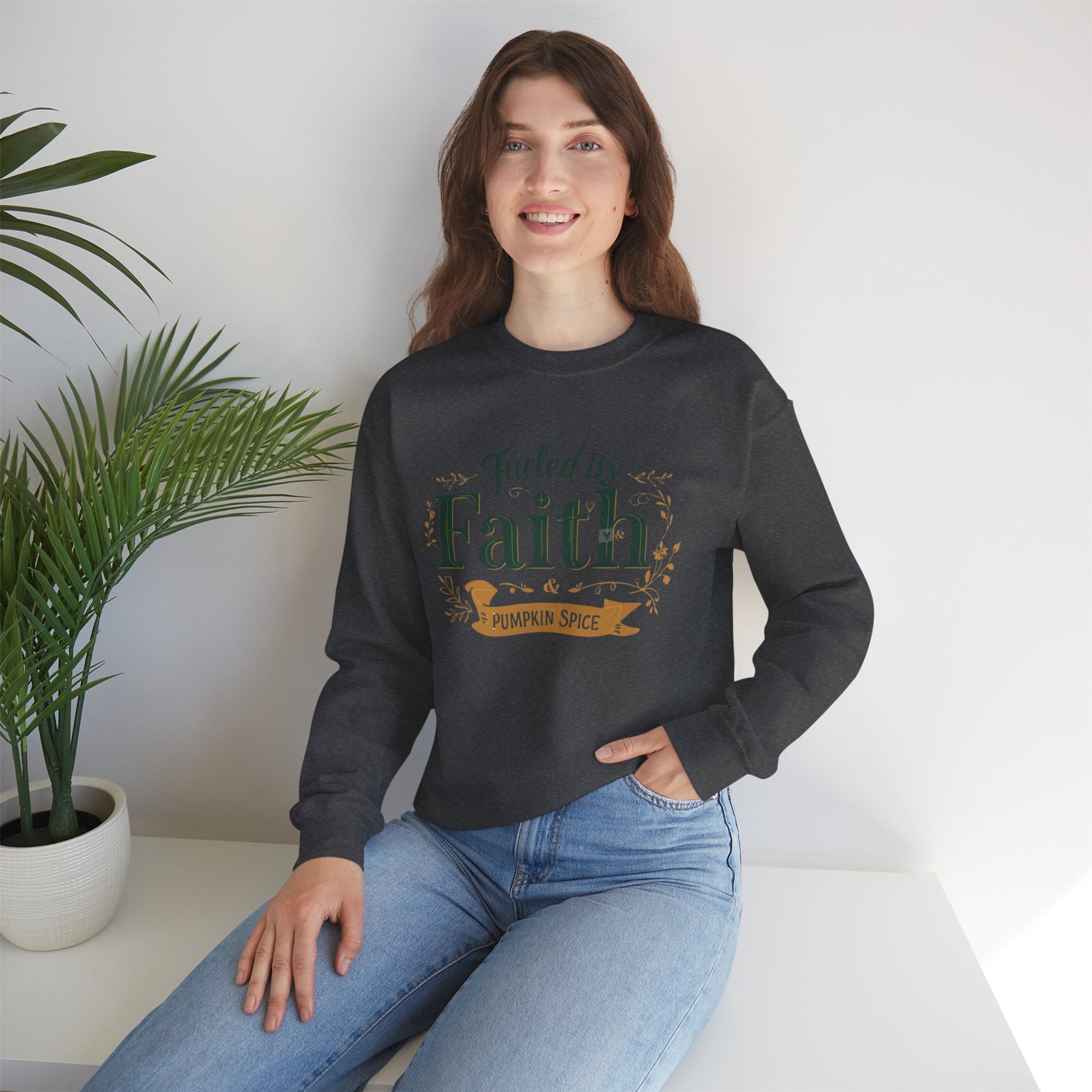 Woman sitting in dark heather “Fueled by Faith & Pumpkin Spice” sweatshirt — cozy Christian autumn outfit styled for comfort.