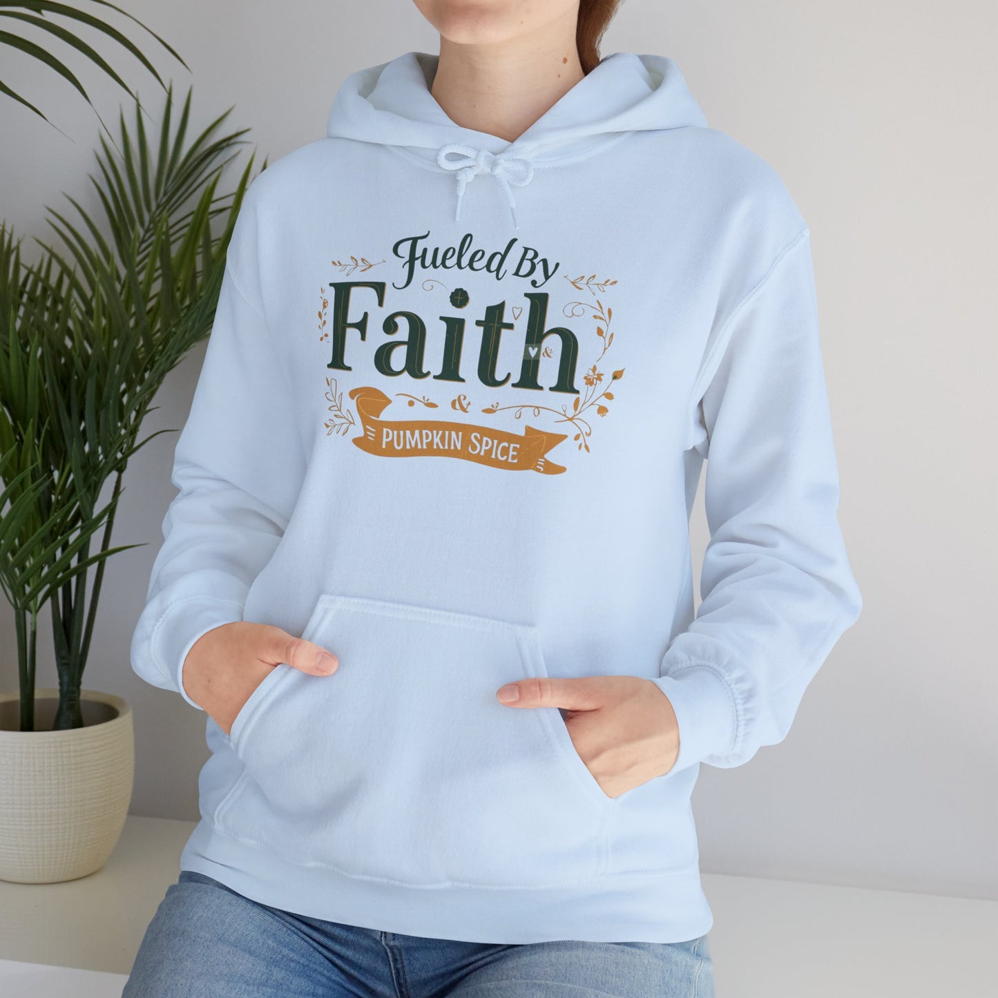 Lifestyle image of woman sitting in light blue “Fueled by Faith & Pumpkin Spice” hoodie — cozy Christian fall apparel for believers.