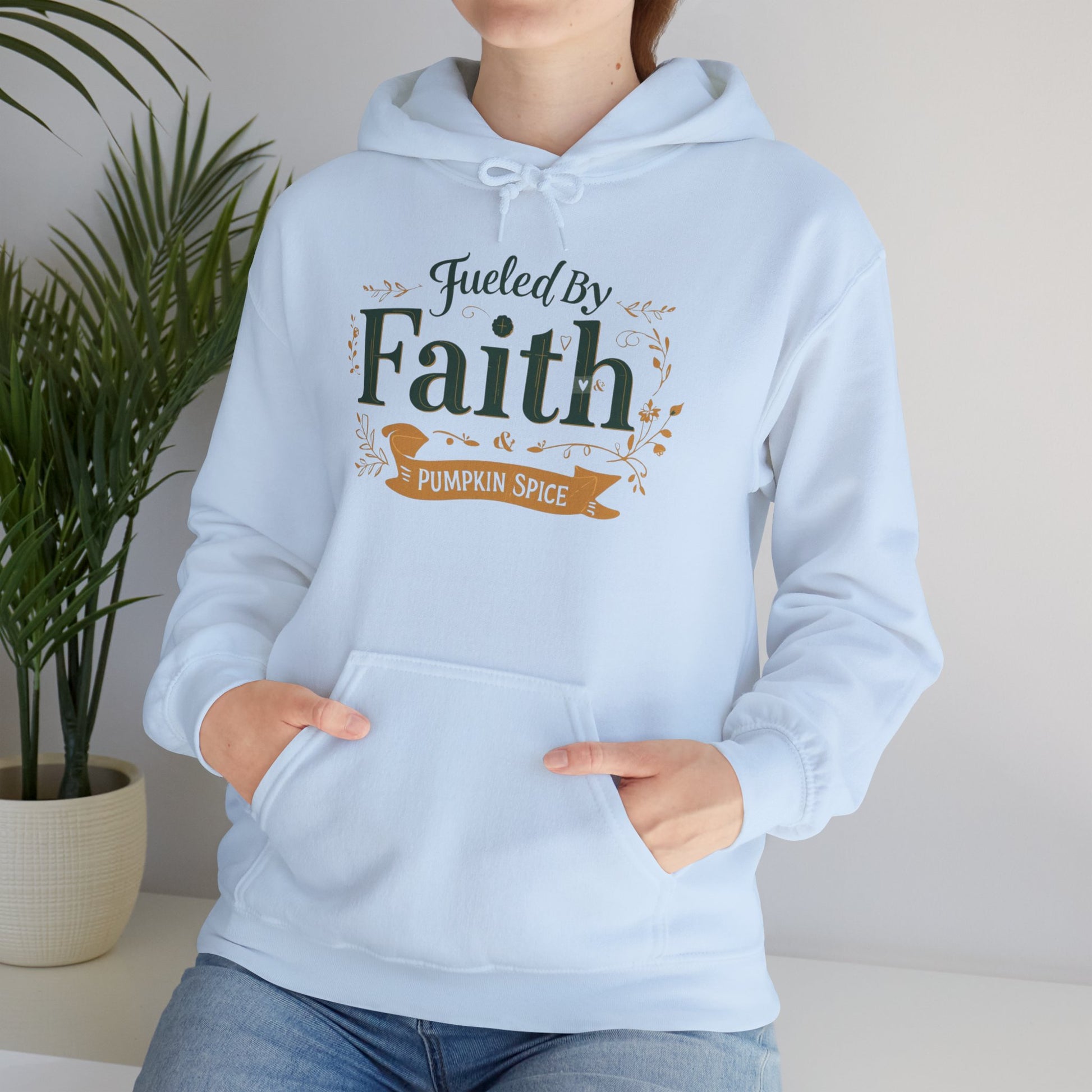 Lifestyle image of woman sitting in light blue “Fueled by Faith & Pumpkin Spice” hoodie — cozy Christian fall apparel for believers.