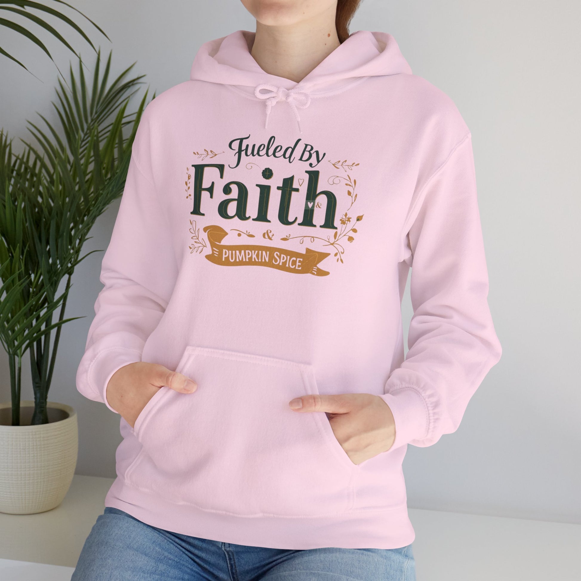 Woman relaxing in light pink “Fueled by Faith & Pumpkin Spice” hoodie — cozy Christian fall lifestyle apparel.