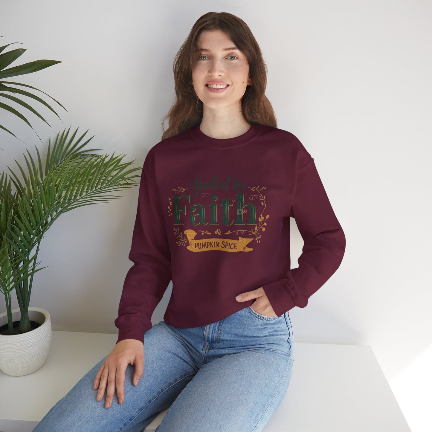 Woman sitting in maroon “Fueled by Faith & Pumpkin Spice” sweatshirt — cozy fall Christian lifestyle apparel scene.