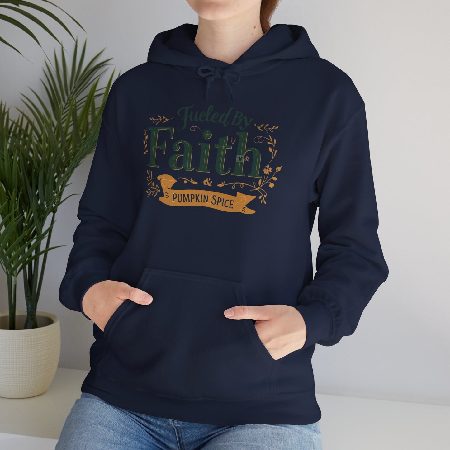 Cozy indoor lifestyle image of navy “Fueled by Faith & Pumpkin Spice” hoodie — Christian fall apparel for faith-filled living.