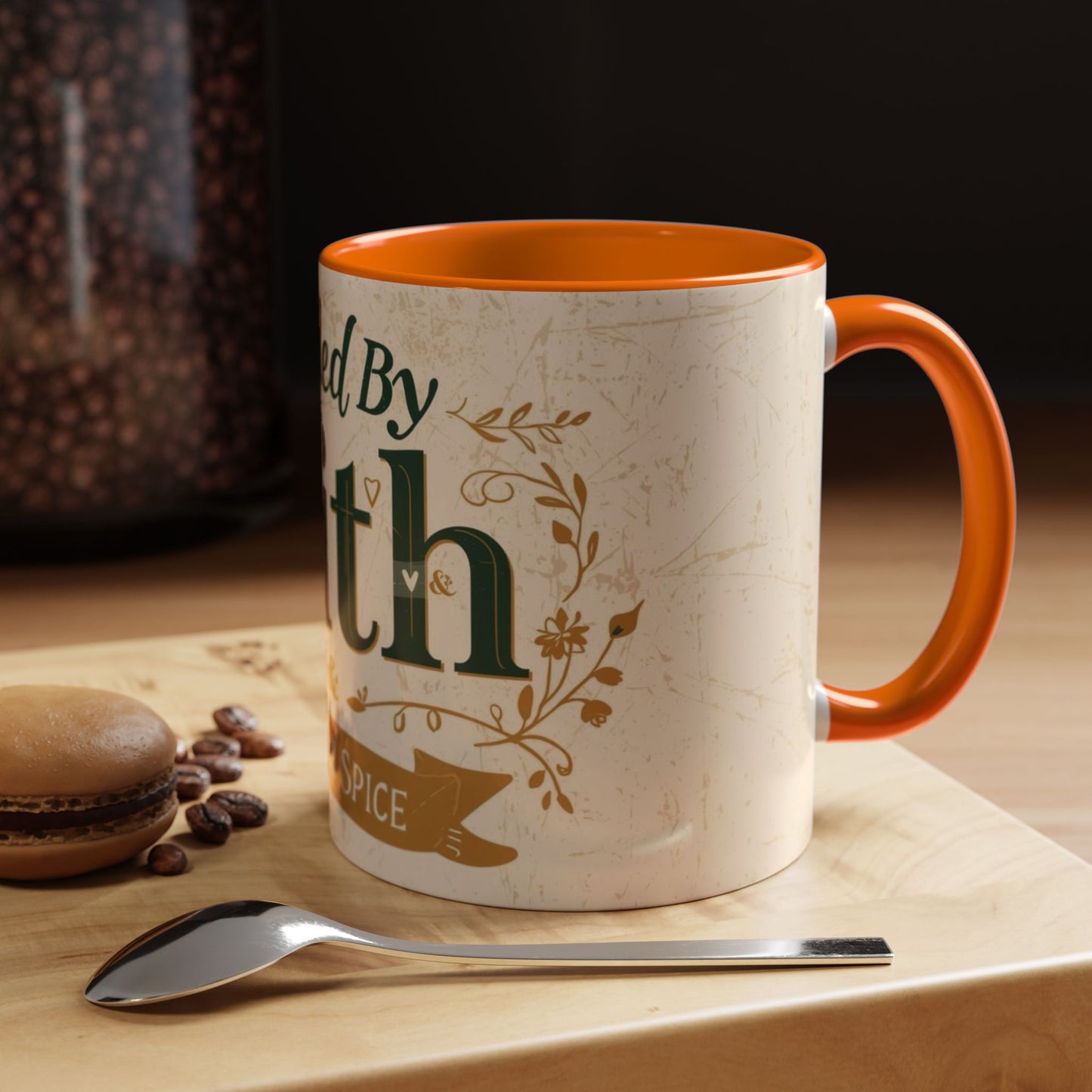 Lifestyle photo of orange “Fueled by Faith & Pumpkin Spice” mug — cozy Christian coffee mug with orange interior styled beside macarons and coffee beans.