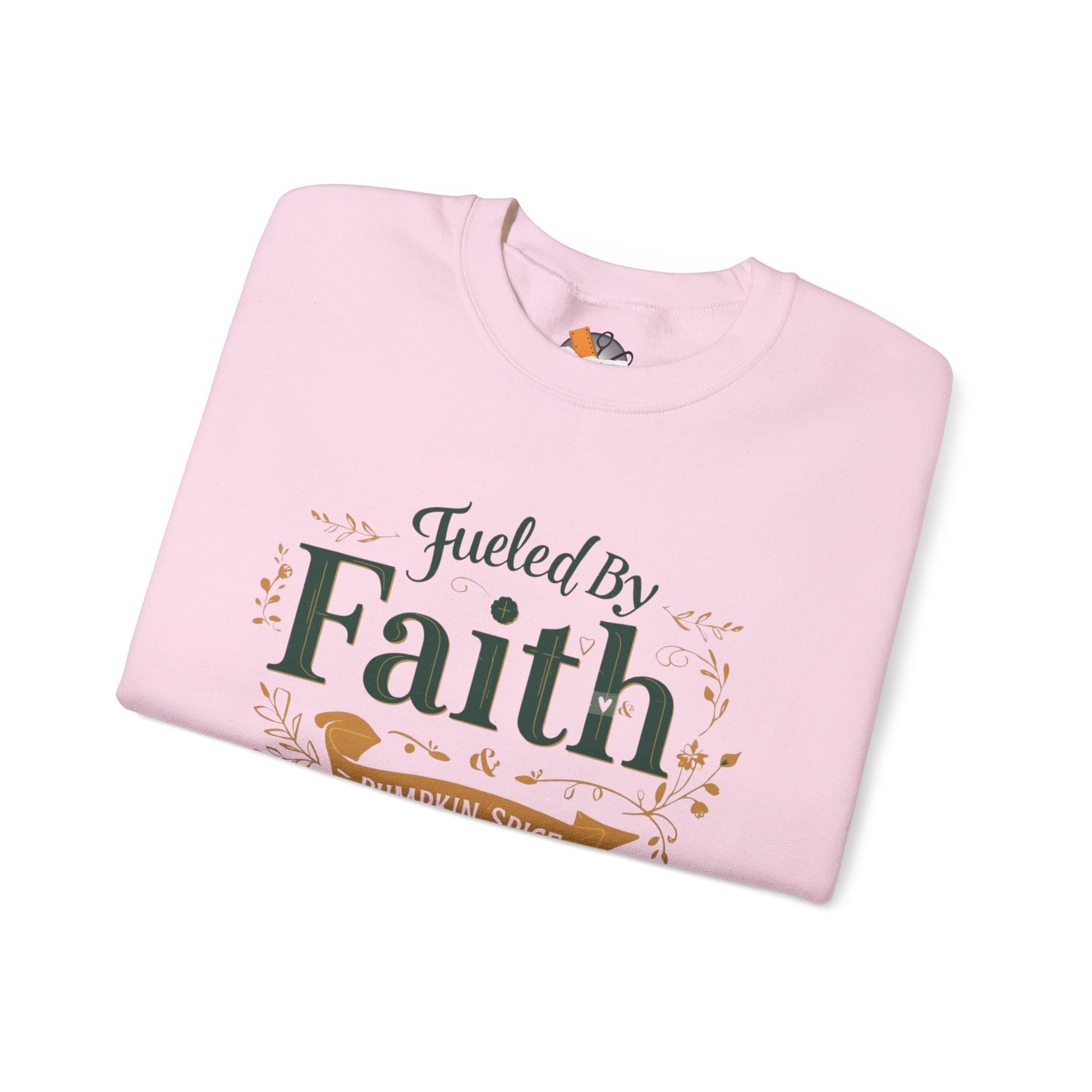 Folded light pink “Fueled by Faith & Pumpkin Spice” crewneck sweatshirt with green and gold lettering — cozy fall Christian apparel mockup.