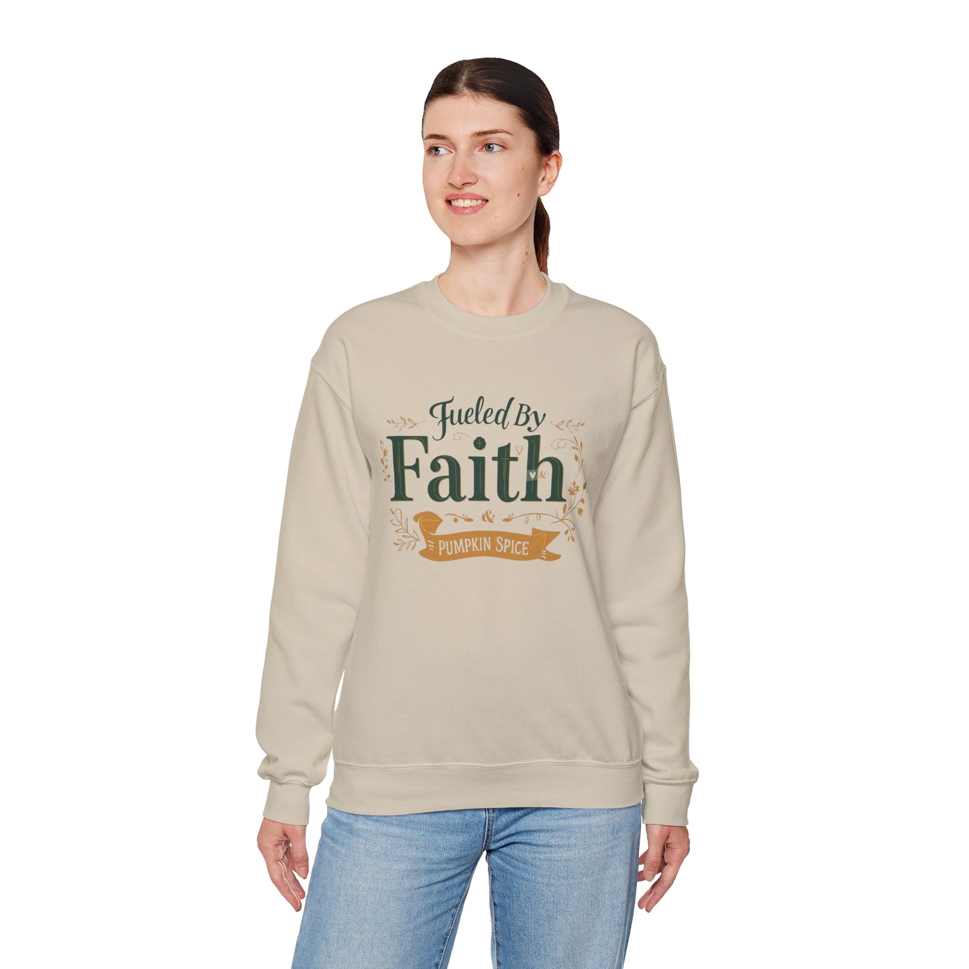 Woman modeling sand “Fueled by Faith & Pumpkin Spice” sweatshirt — cozy Christian unisex crewneck perfect for fall.
