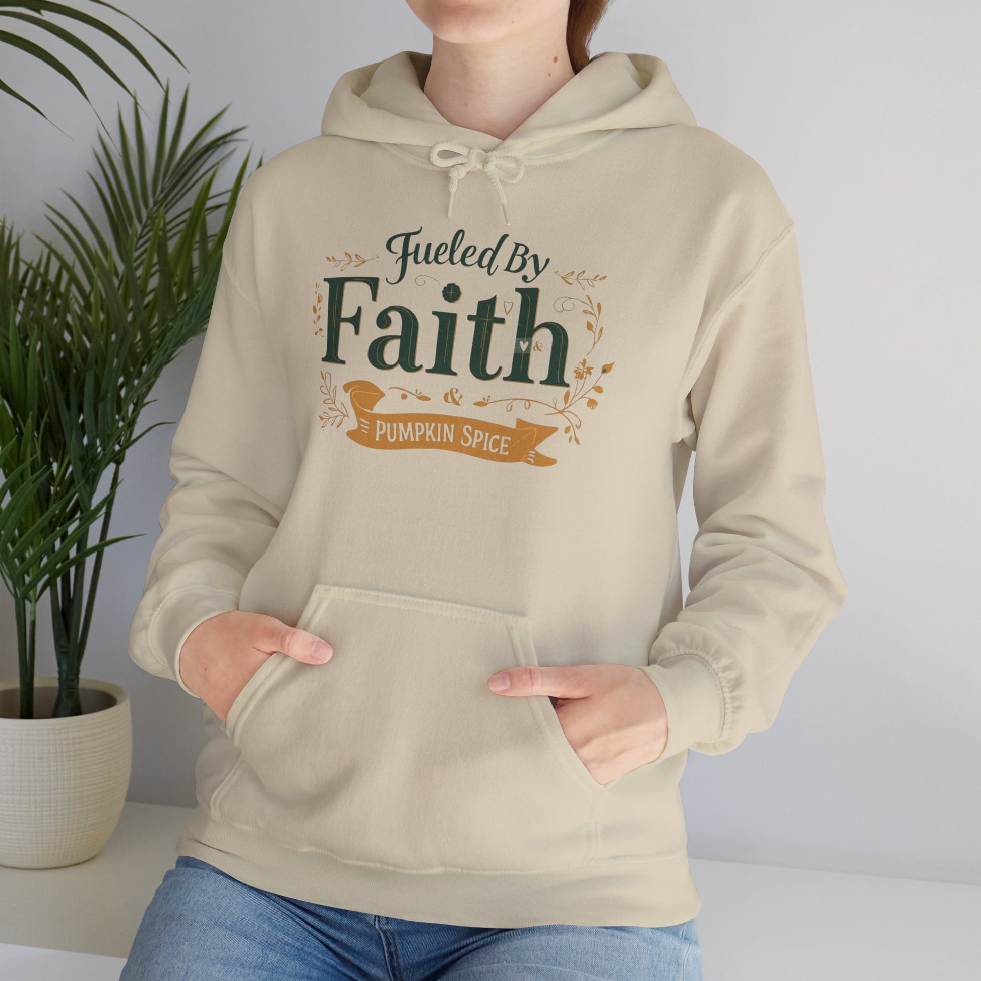 Lifestyle photo of woman in sand “Fueled by Faith & Pumpkin Spice” hoodie — cozy Christian fall apparel for everyday wear.
