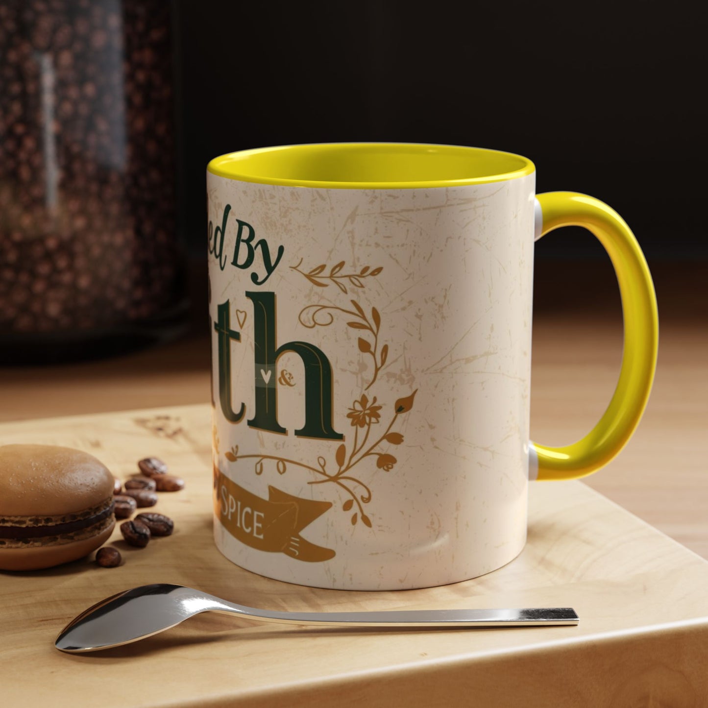 Lifestyle photo of yellow “Fueled by Faith & Pumpkin Spice” accent mug — cozy Christian coffee mug styled with macarons and coffee beans.