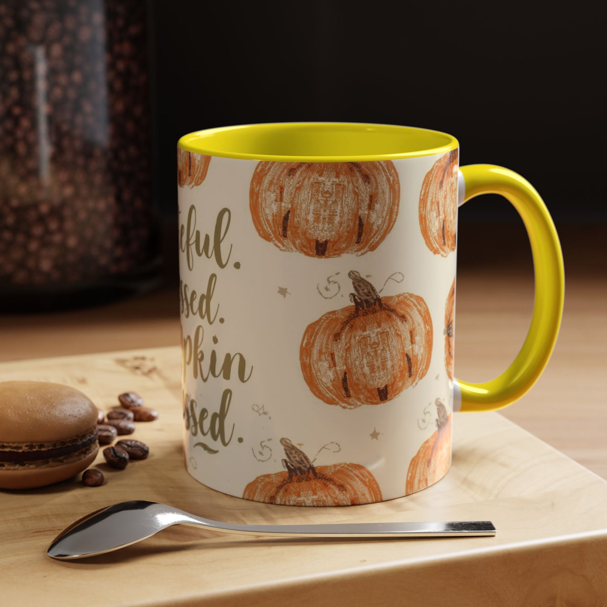 Grateful, Blessed & Pumpkin Obsessed yellow accent mug on cozy fall coffee table with macaron, coffee beans, and silver spoon.