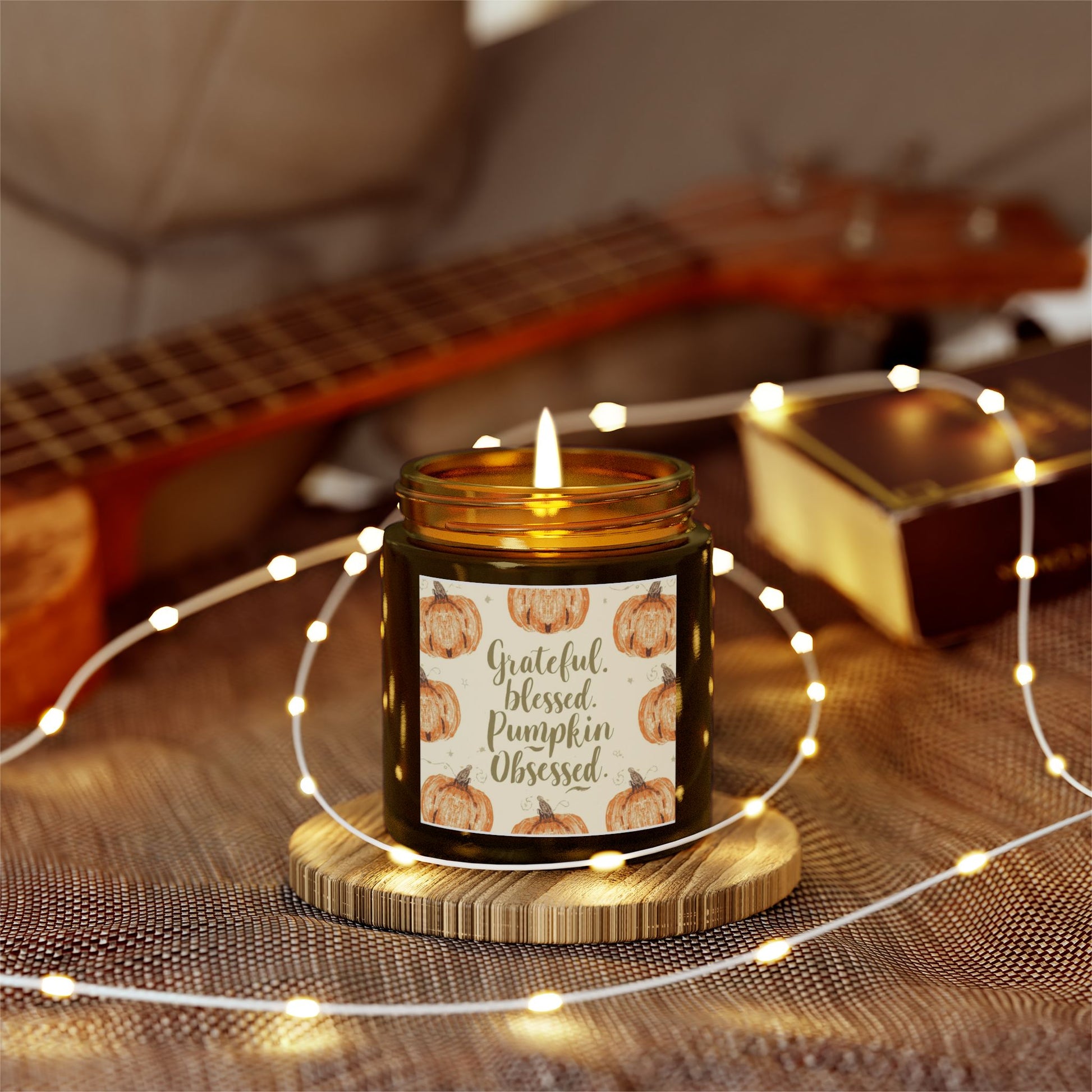 “Grateful, Blessed & Pumpkin Obsessed” candle surrounded by string lights — sweet blackberry vanilla scent for cozy autumn nights.