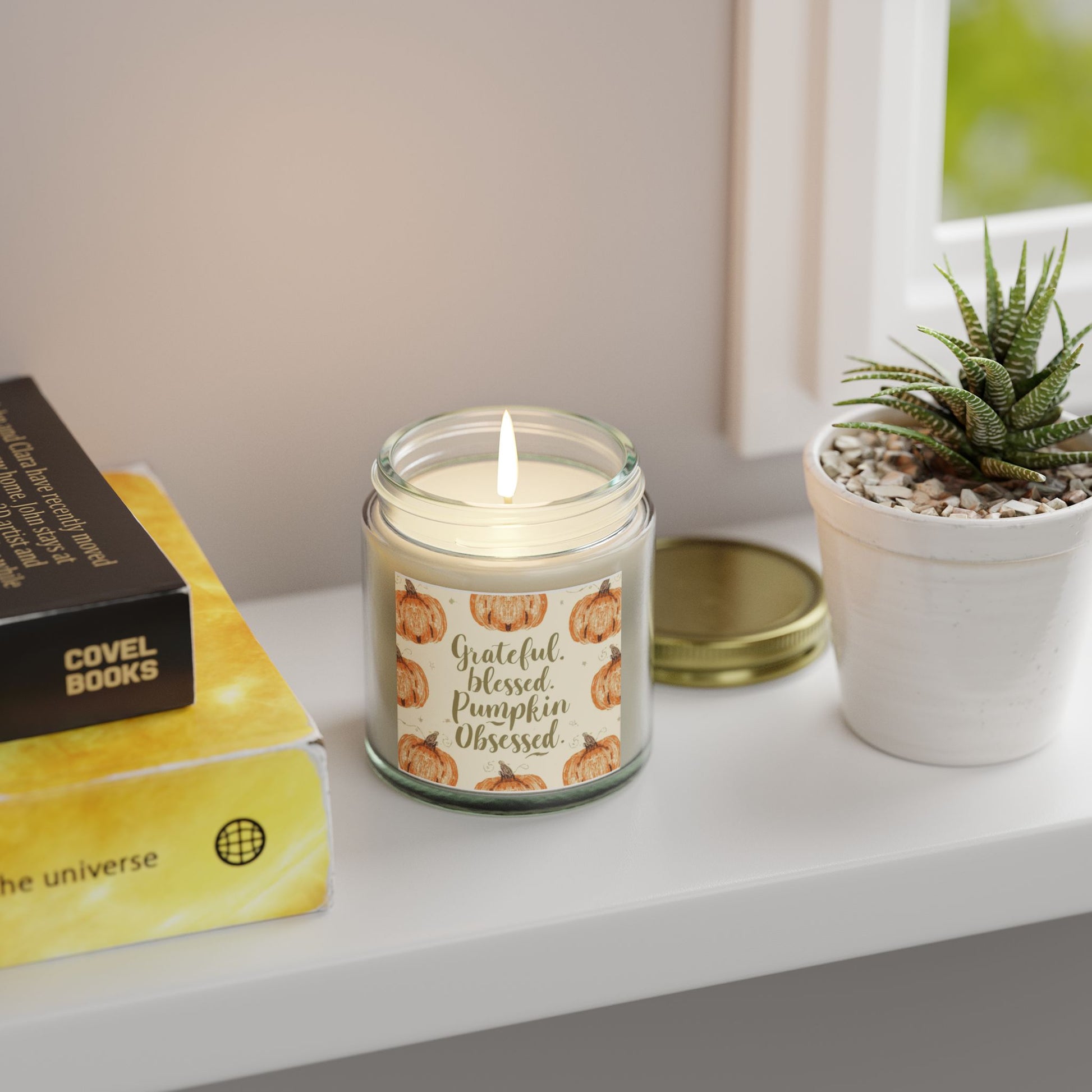 “Grateful, Blessed & Pumpkin Obsessed” clear candle glowing by window — fragrance-free unscented soy candle for calm, natural fall ambiance.