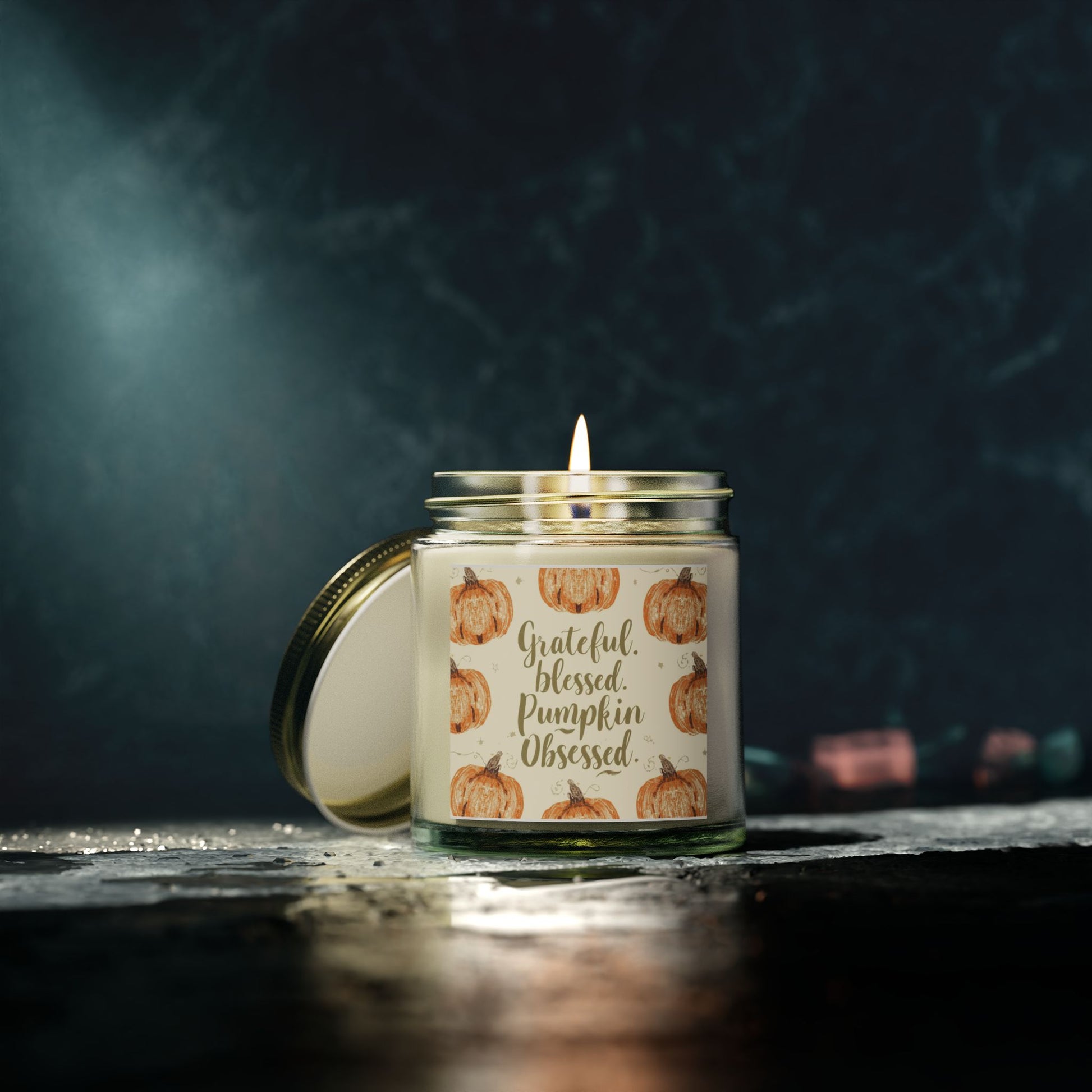 Lit “Grateful, Blessed & Pumpkin Obsessed” clear candle glowing softly — smooth vanilla bean candle creating sweet, relaxing fall ambiance.