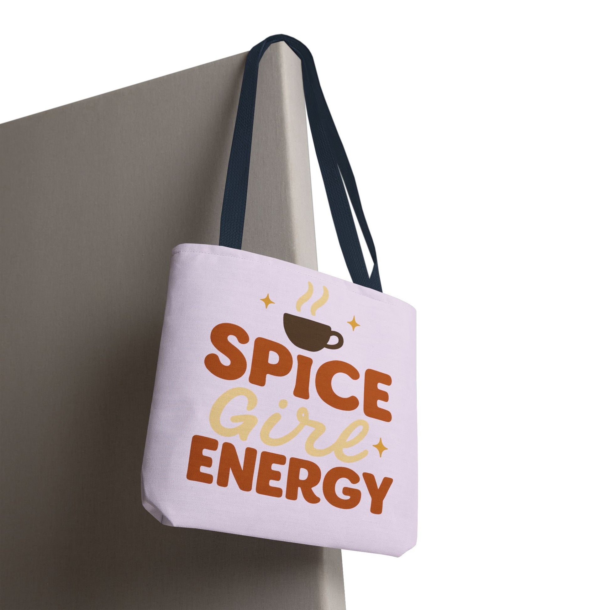 “Spice Girl Energy” tote bag in lilac with navy straps hanging on wall — cozy pastel coffee-lover tote for everyday or gift use.