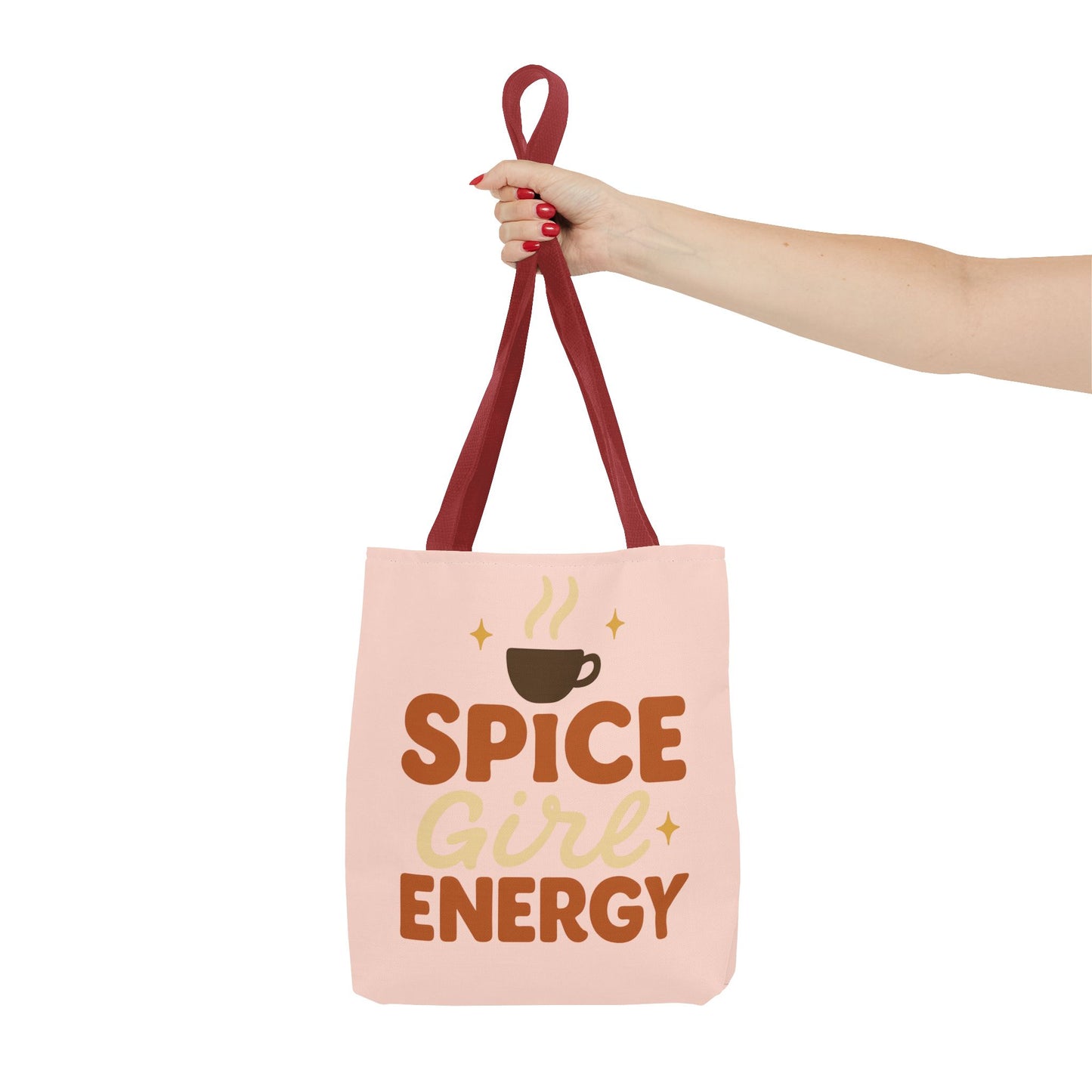 Red-handled pale pink “Spice Girl Energy” tote bag held in hand — soft pastel tote for coffee lovers and cozy autumn outfits.
