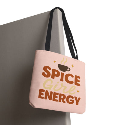 “Spice Girl Energy” tote bag in pale pink with black handles hanging on wall — stylish coffee-aesthetic tote for gifting and everyday use.