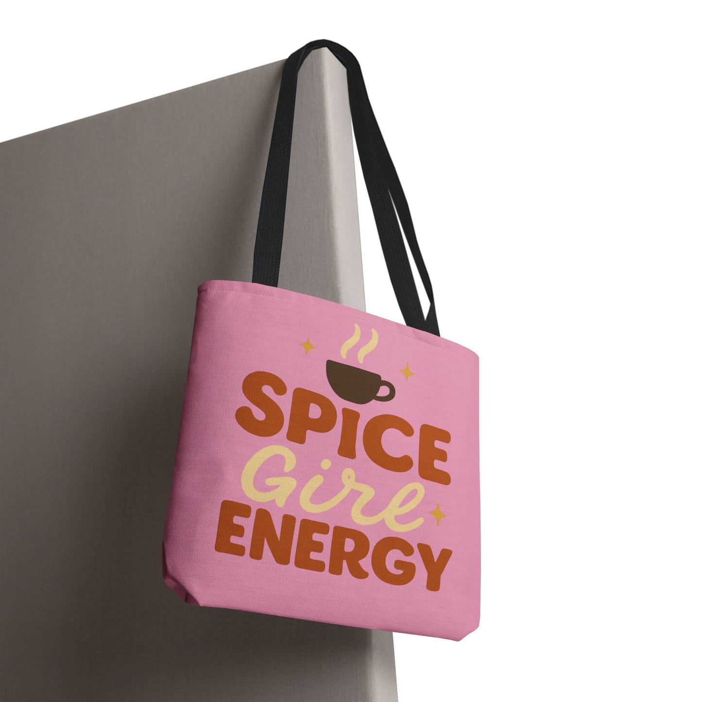 “Spice Girl Energy” tote bag with black straps hanging on wall — pink fall tote with coffee cup graphic and inspirational lettering.