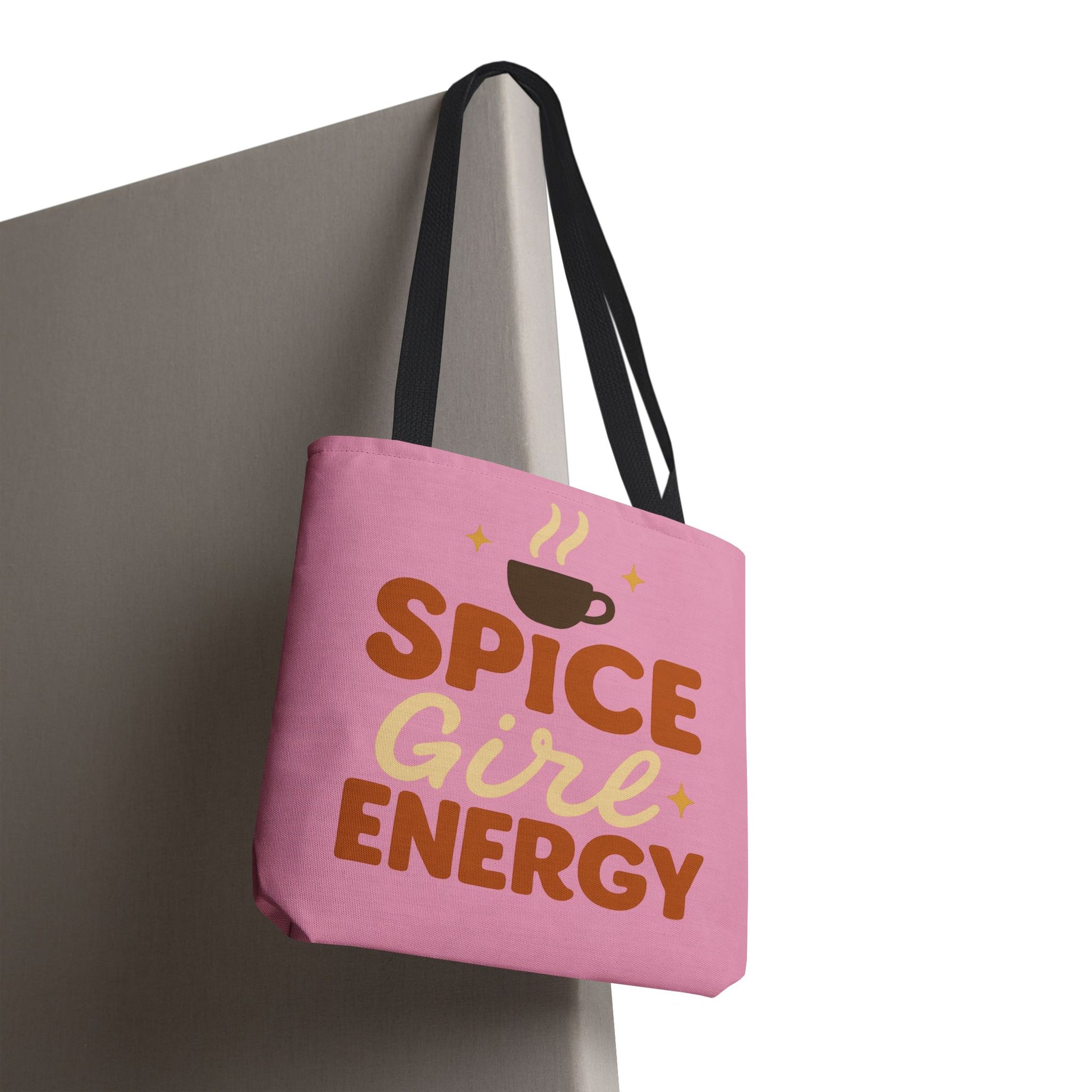 “Spice Girl Energy” tote bag with black straps hanging on wall — pink fall tote with coffee cup graphic and inspirational lettering.