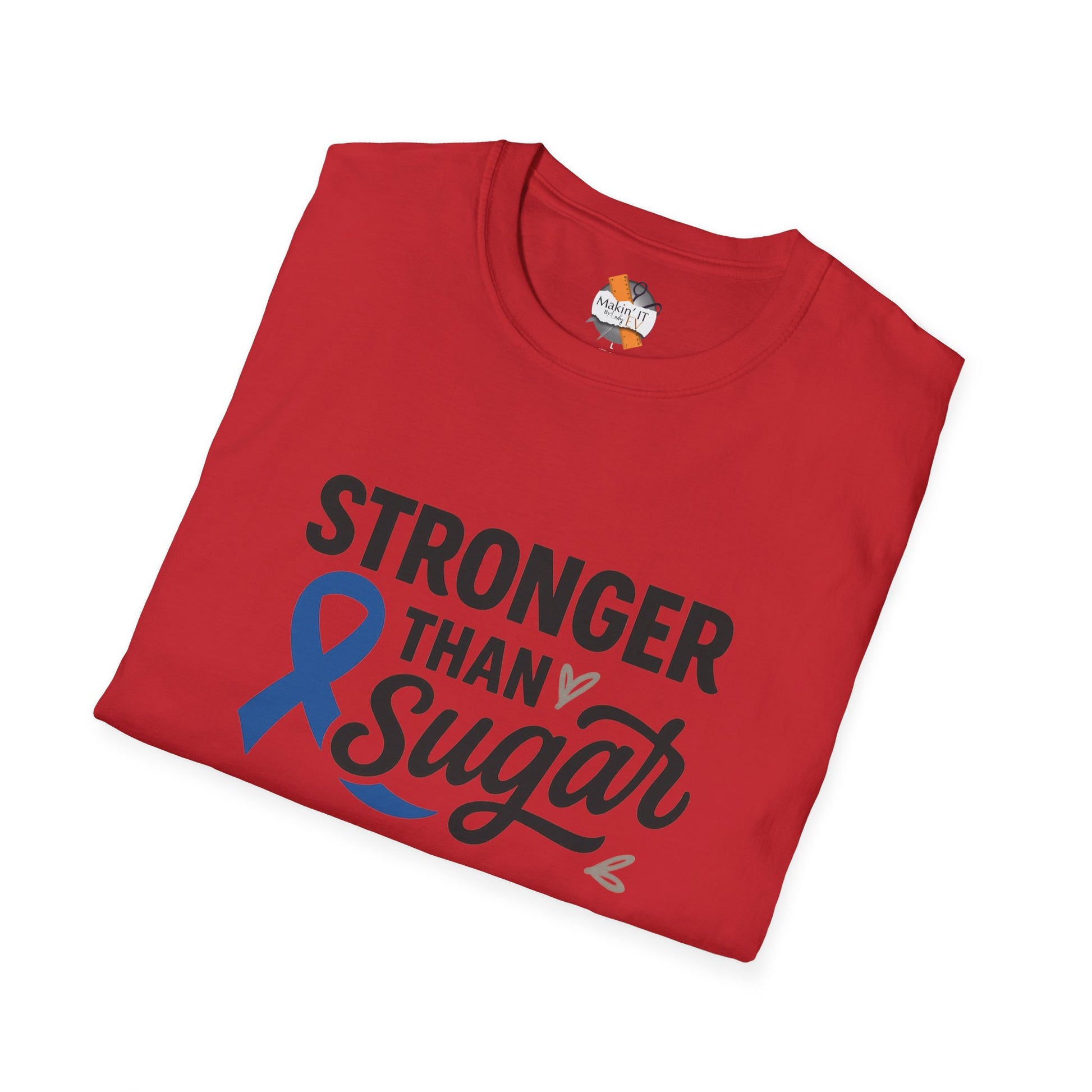 Folded red Stronger Than Sugar adult t-shirt — motivational diabetes awareness design with blue ribbon and heart accents for strength and hope.
