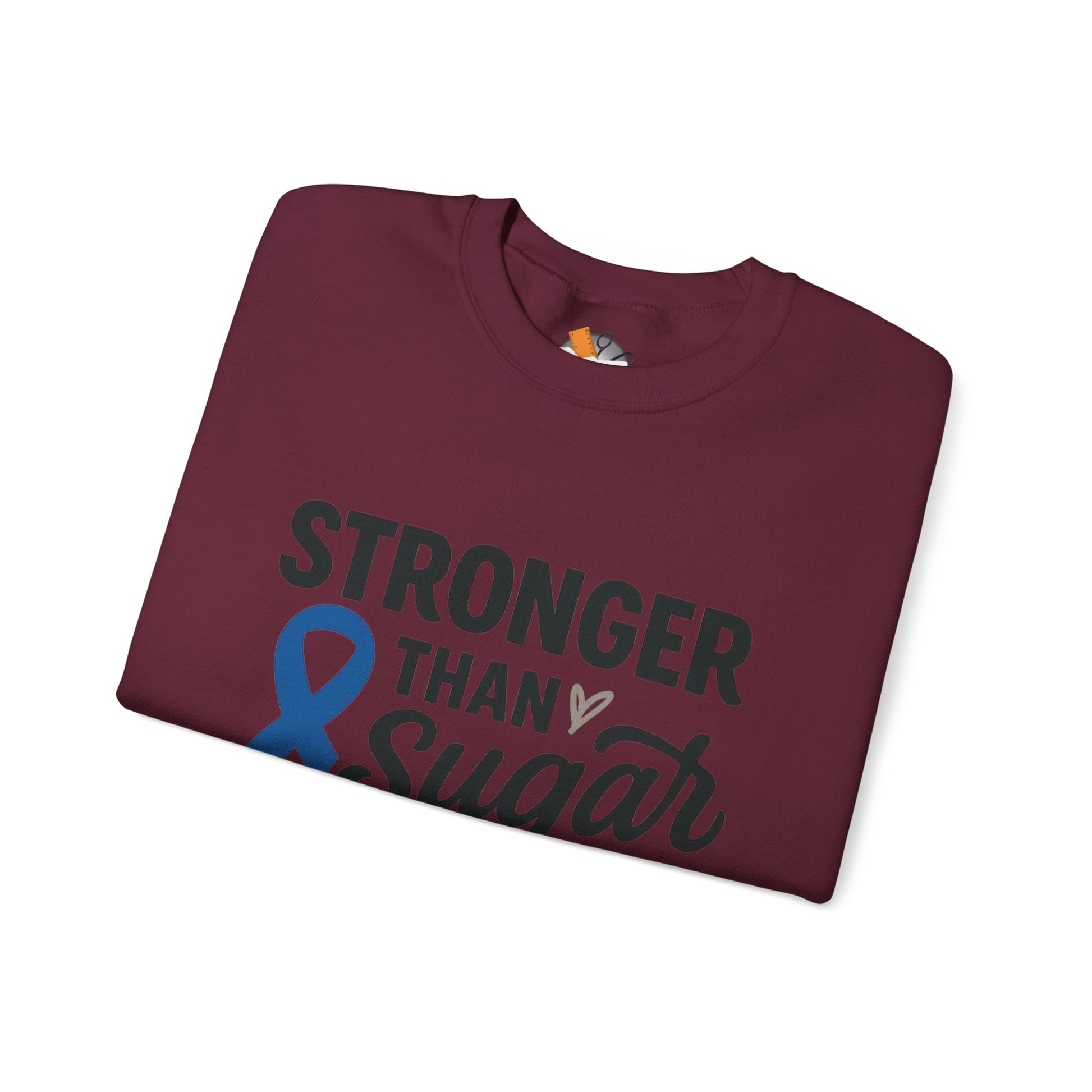 Folded maroon Stronger Than Sugar sweatshirt featuring blue diabetes awareness ribbon — soft unisex sweater symbolizing strength and health advocacy.