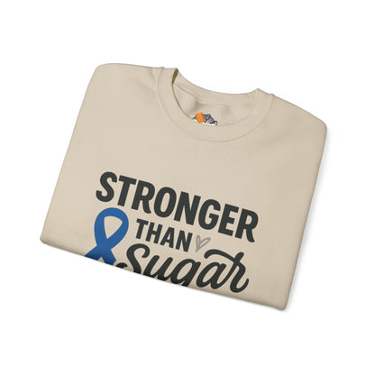 Folded sand Stronger Than Sugar sweatshirt — soft unisex sweater featuring blue awareness ribbon supporting diabetes education and advocacy.