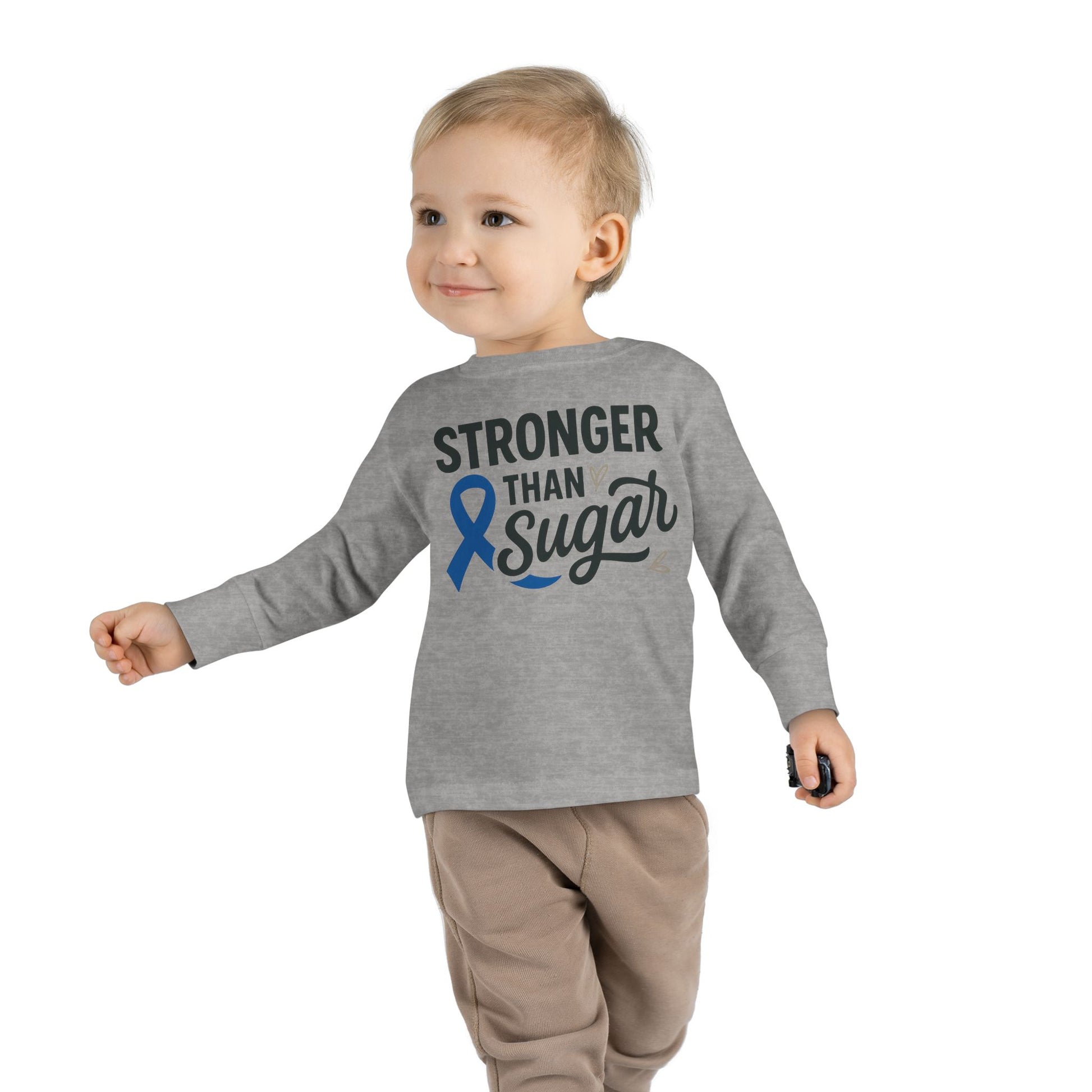 Toddler boy wearing heather gray Stronger Than Sugar shirt — kids long sleeve awareness top featuring blue diabetes ribbon and motivational design.