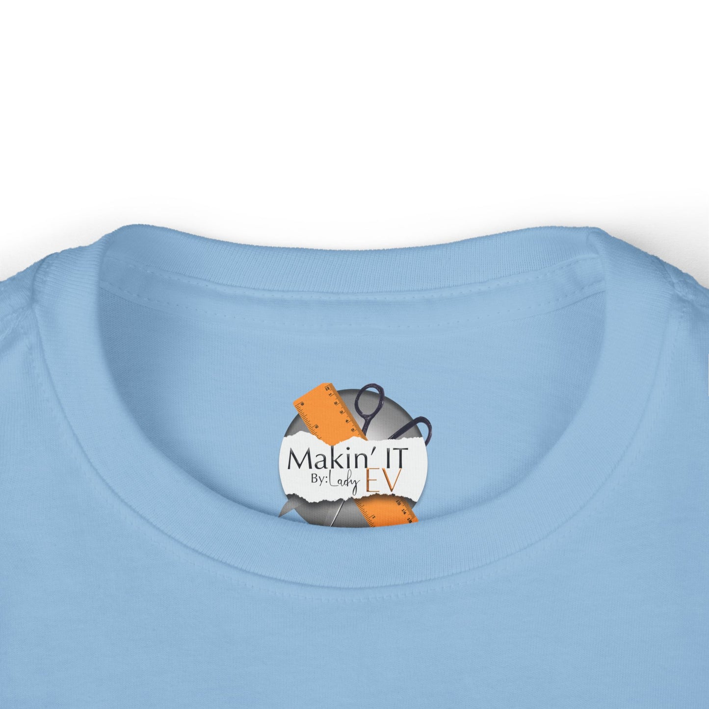 Close-up of Makin’ It By Lady Ev neck label on light blue Stronger Than Sugar toddler shirt — premium quality finish on awareness apparel for children.
