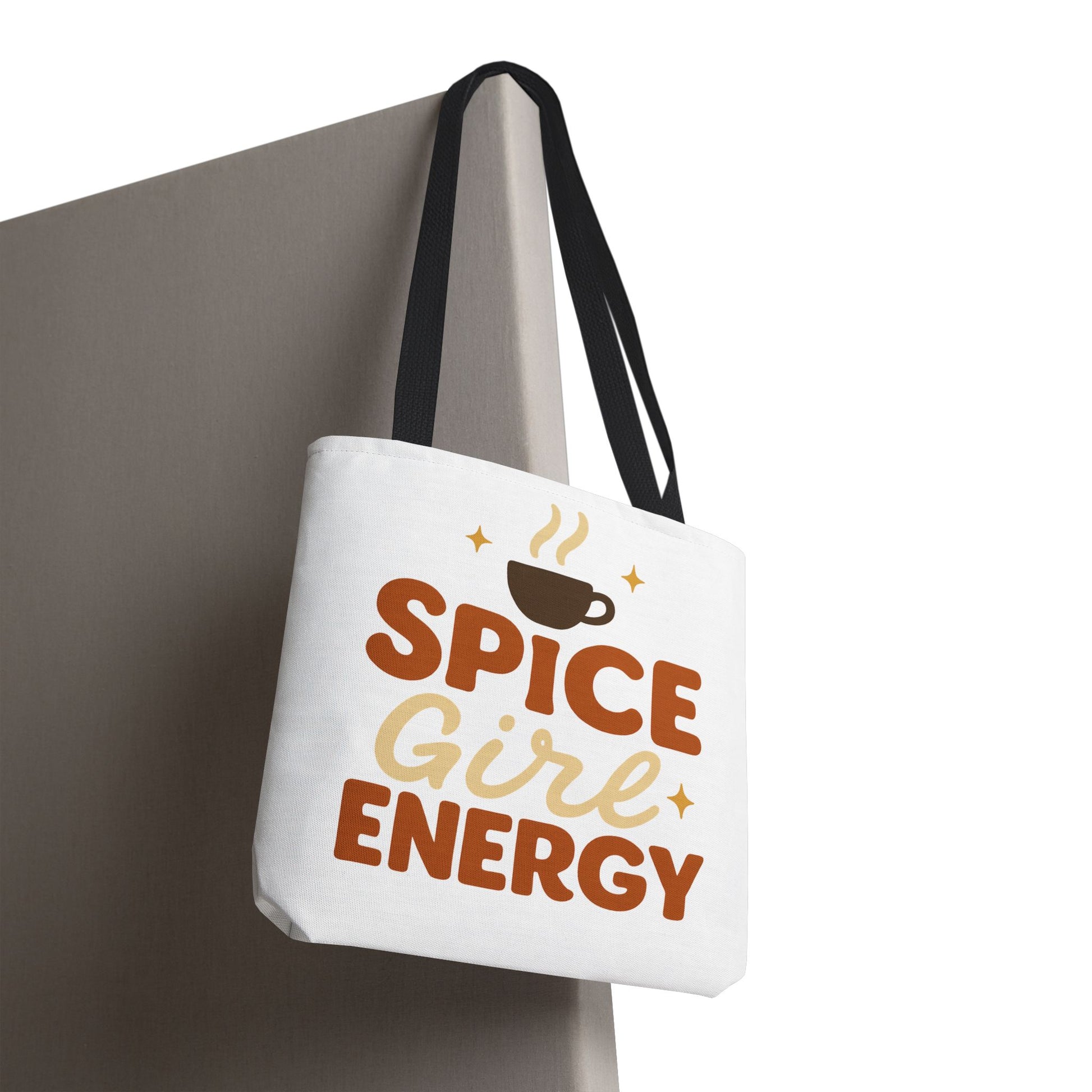 White “Spice Girl Energy” tote bag with black straps hanging on wall — trendy coffee-themed tote perfect for fall and everyday use.