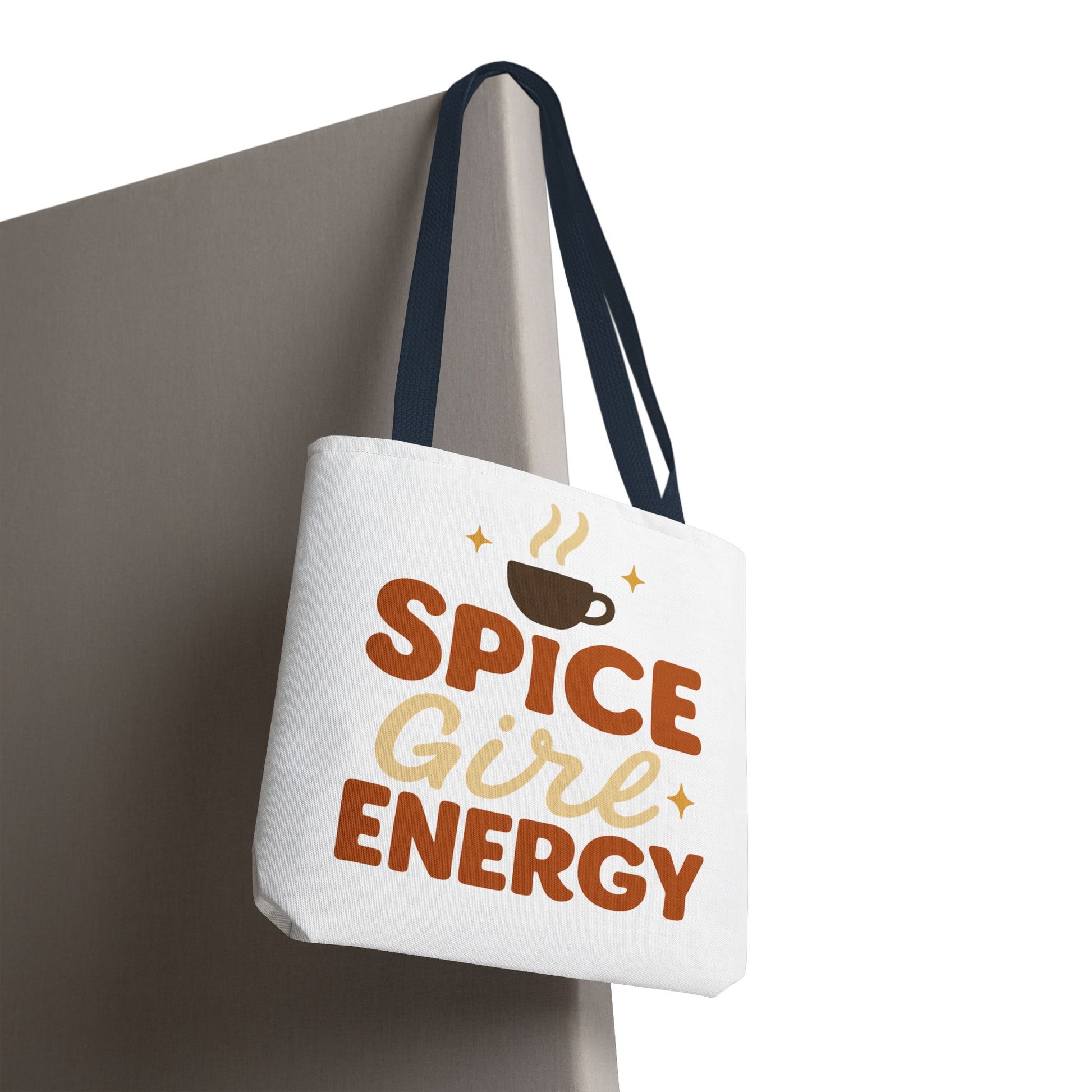 White “Spice Girl Energy” tote bag with navy handles hanging on wall — trendy coffee aesthetic tote for pumpkin spice lovers.