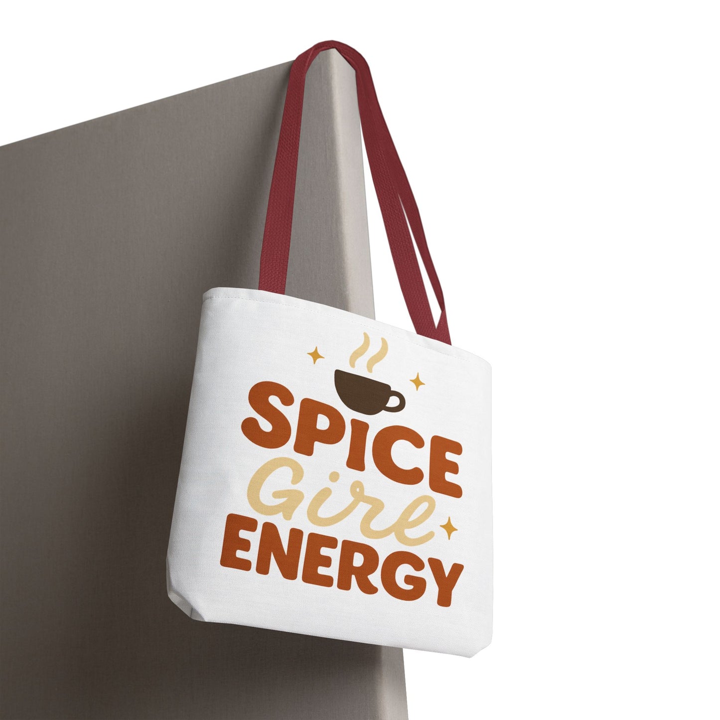 White “Spice Girl Energy” tote bag with red straps hanging on wall — chic autumn tote for coffee lovers and pumpkin spice fans.