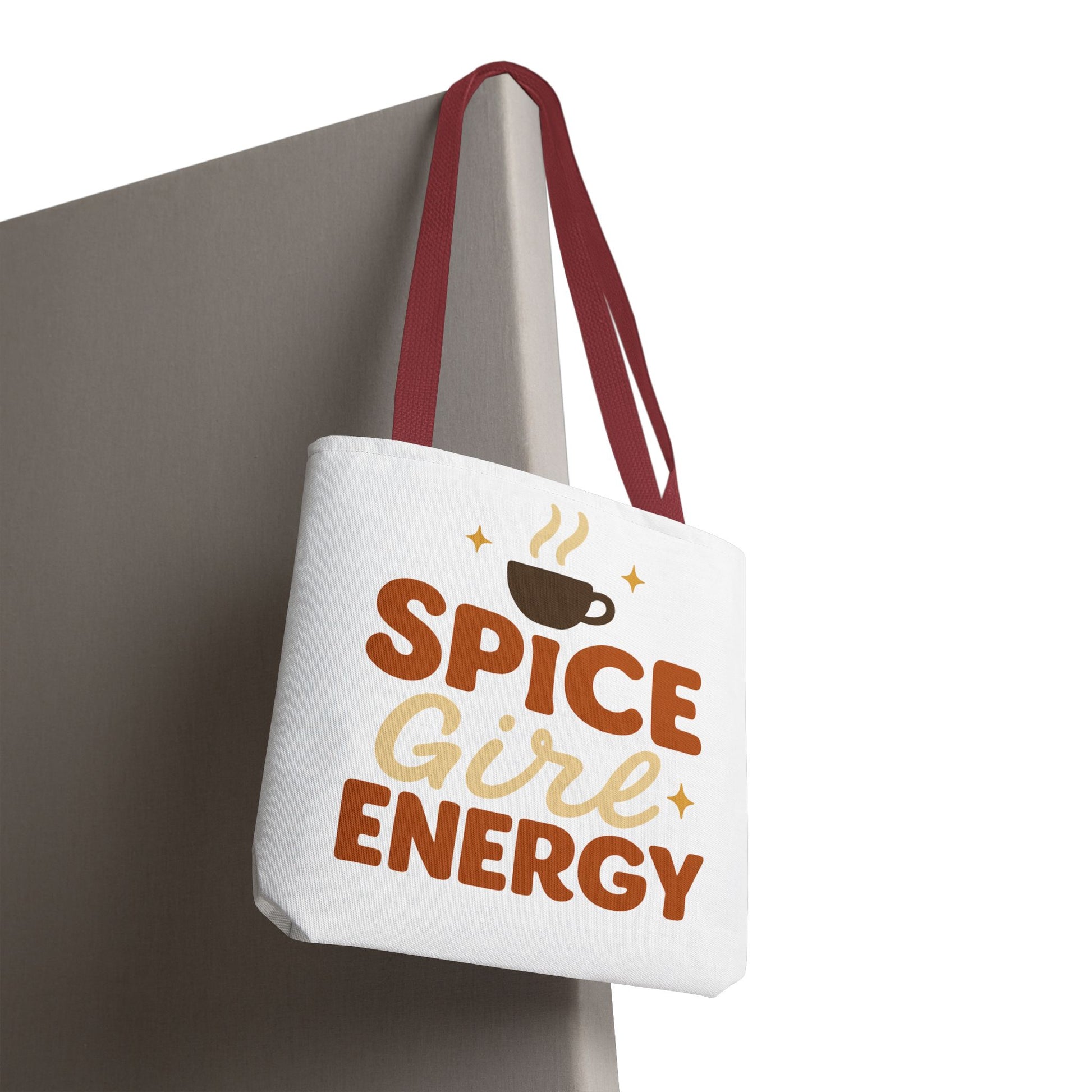 White “Spice Girl Energy” tote bag with red straps hanging on wall — chic autumn tote for coffee lovers and pumpkin spice fans.