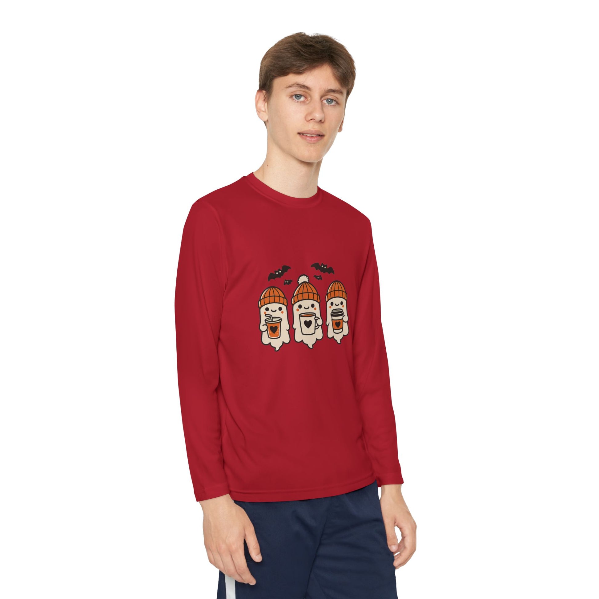 Young Male model wearing a red long sleeve Halloween shirt with three cute ghosts in orange beanies sipping coffee under bats, designed by Makin’ It By Lady Ev.